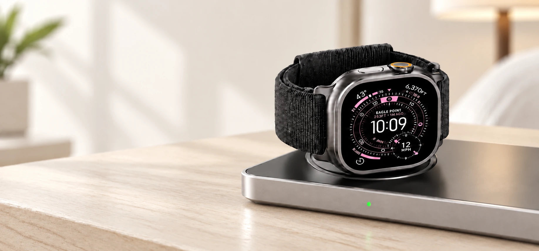 Smartwatch resting on the right charging puck of a gray rectangular charging base.