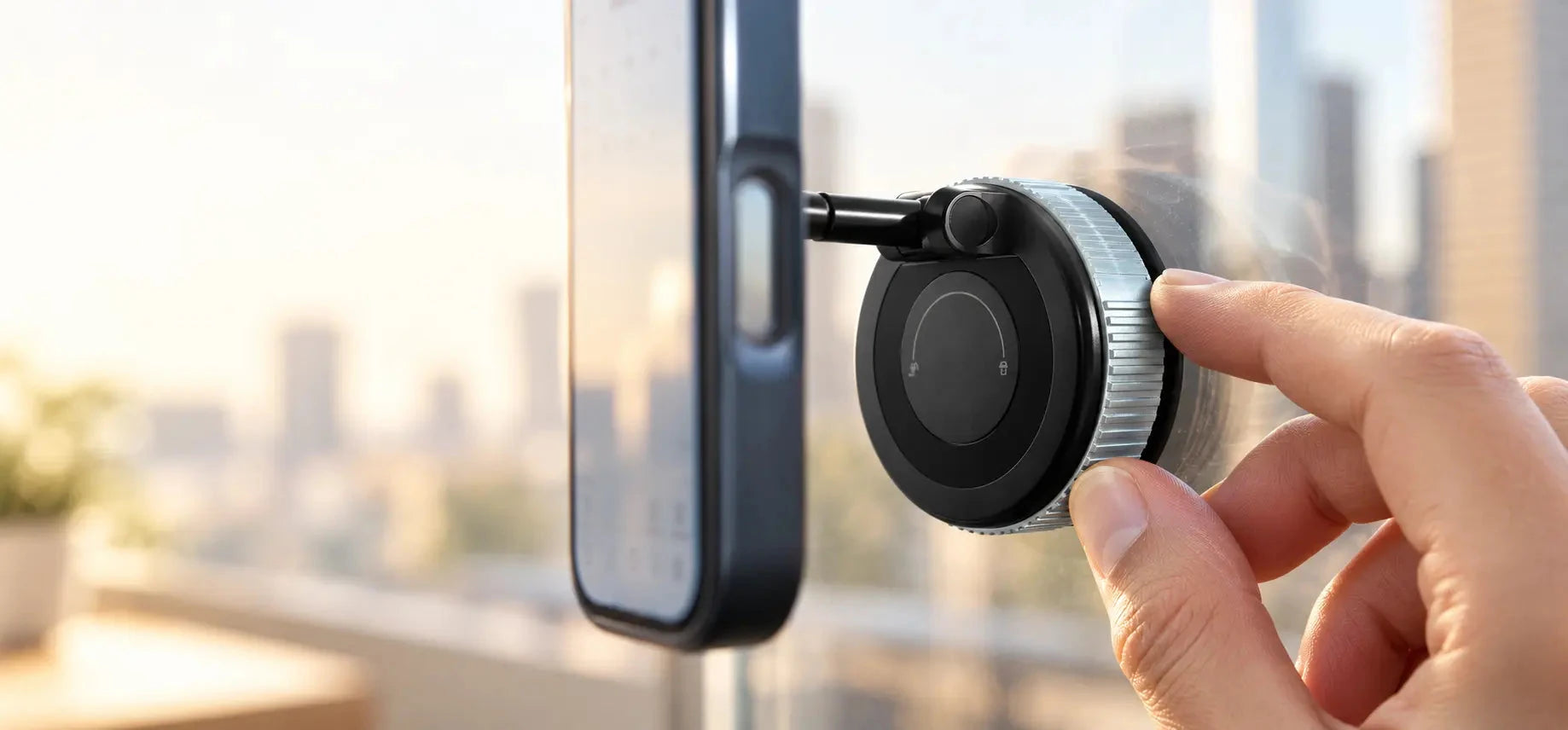 Finger turning the locking base of a black suction phone mount attached to glass.