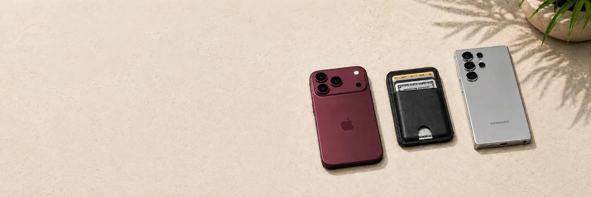 Black magnetic card wallet between a burgundy phone and a silver phone.